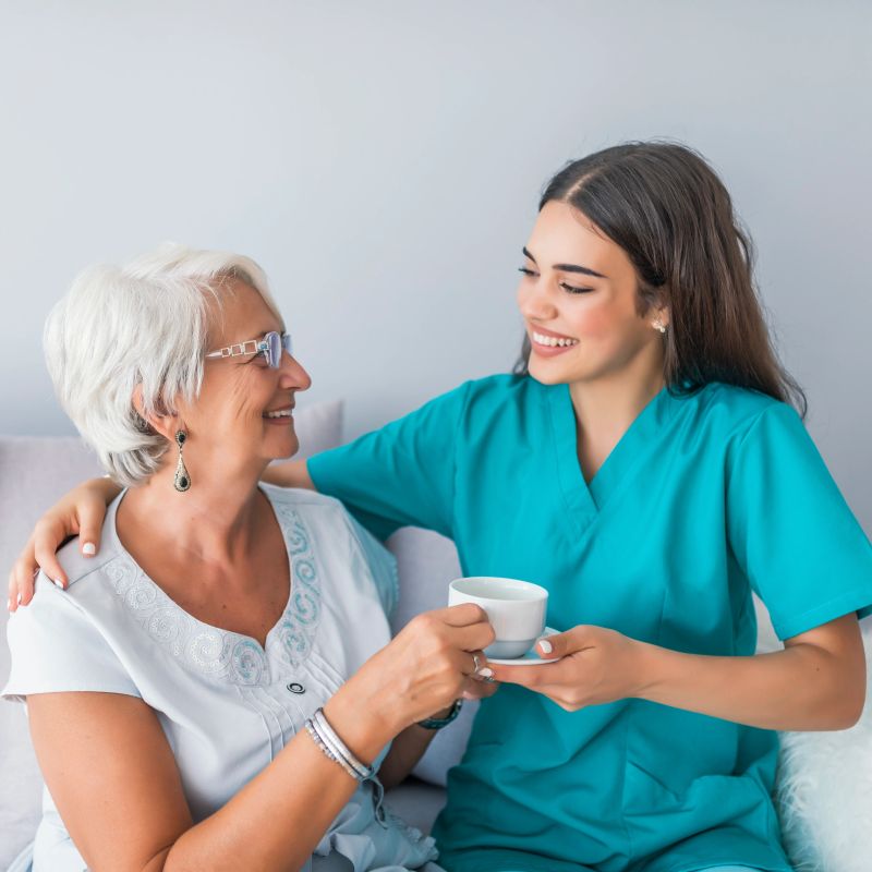Caregiver and elderly woman sharing tea